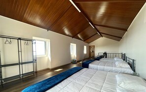 Une chambre avec deux lits, un plancher en bois, une armoire en métal et un plafond en pente.