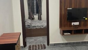 Une chambre à coucher comprenant un lit, un téléviseur fixé au mur, une armoire et une petite table.