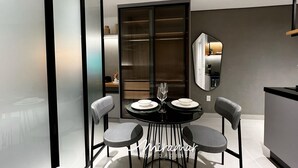 A modern dining area with a black table, two grey chairs, and a glass wine glass. - Vert House (Joao Pessoa)