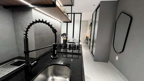 A modern kitchen with a stainless steel sink, a black faucet, and a gas stove. - Vert House (Joao Pessoa)