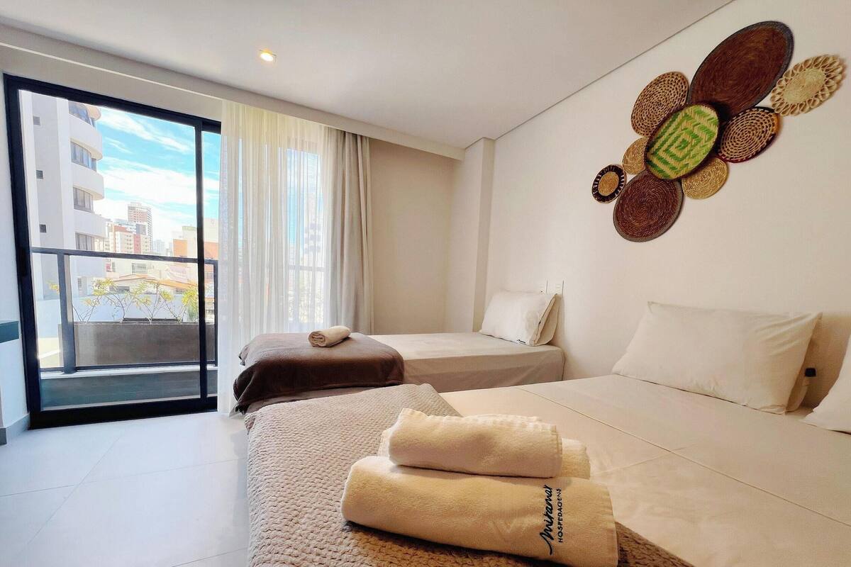 A hotel room with two beds, a large window, and a decorative wall piece.