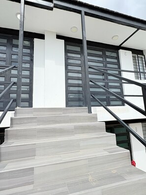 Una scala conduce a un edificio dal design moderno, con ringhiera in metallo e una serie di finestre.