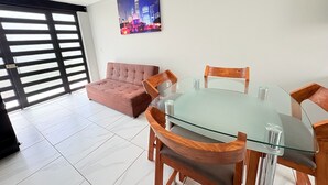 Ein modernes Zimmer mit einem Glastisch, Holzstühlen, einem rosa Sofa und einem Stadtbild an der Wand.