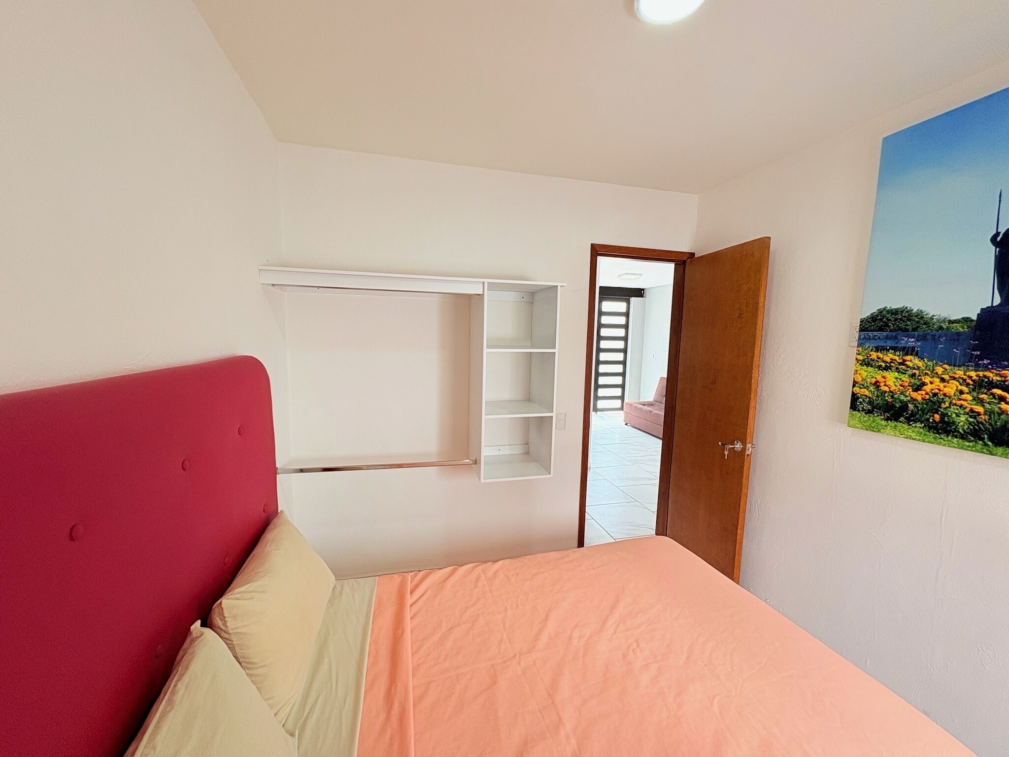 A bedroom with a bed, a wardrobe, and a door leading to another room.