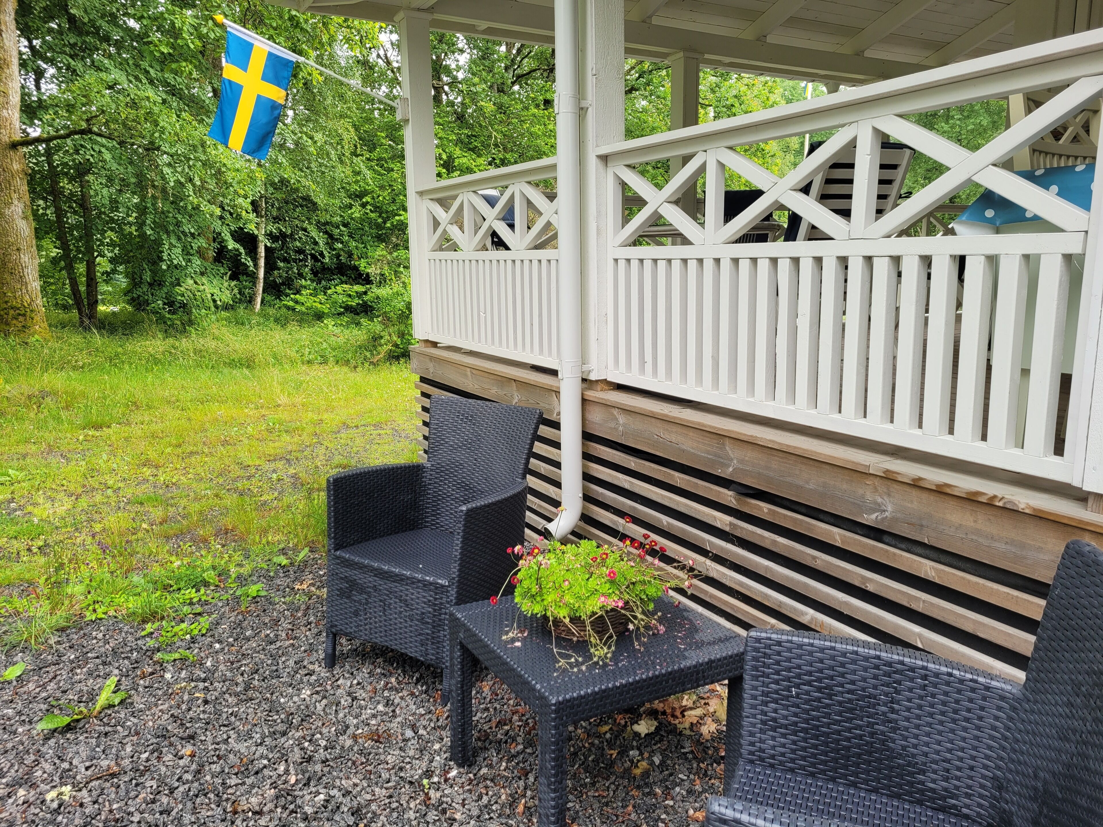 A covered outdoor seating area with wicker furniture and a flag.