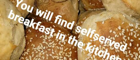 A collection of self-served breakfast rolls with sesame seeds.