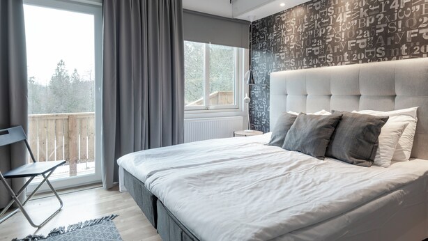 Una camera da letto con un letto grande, una finestra con tende, vista sull'esterno e un muro decorato con un motivo.