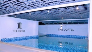 Een modern binnenzwembad met betegelde wanden en plafond, aangeduid met 'THE LOFTEL'.