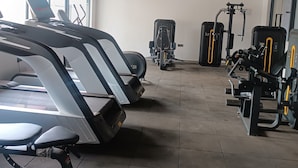 Een fitnessruimte met loopbanden, gewichtapparaten en een groot raam.