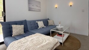 Un soggiorno moderno con un divano blu, un tavolino da caffè bianco e una coperta beige.