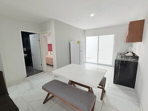 Una cocina compacta con comedor, una banca y un refrigerador.