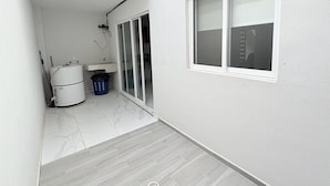 A narrow corridor with a white wall, a window, a sink, and a mop. - Residencial Gran Cobae Triplex A (Tonalá)