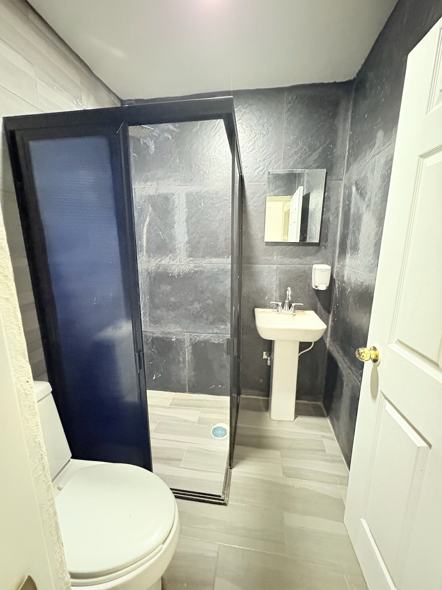 Een badkamer met een wit toilet, een wastafel, een spiegel en een douche.