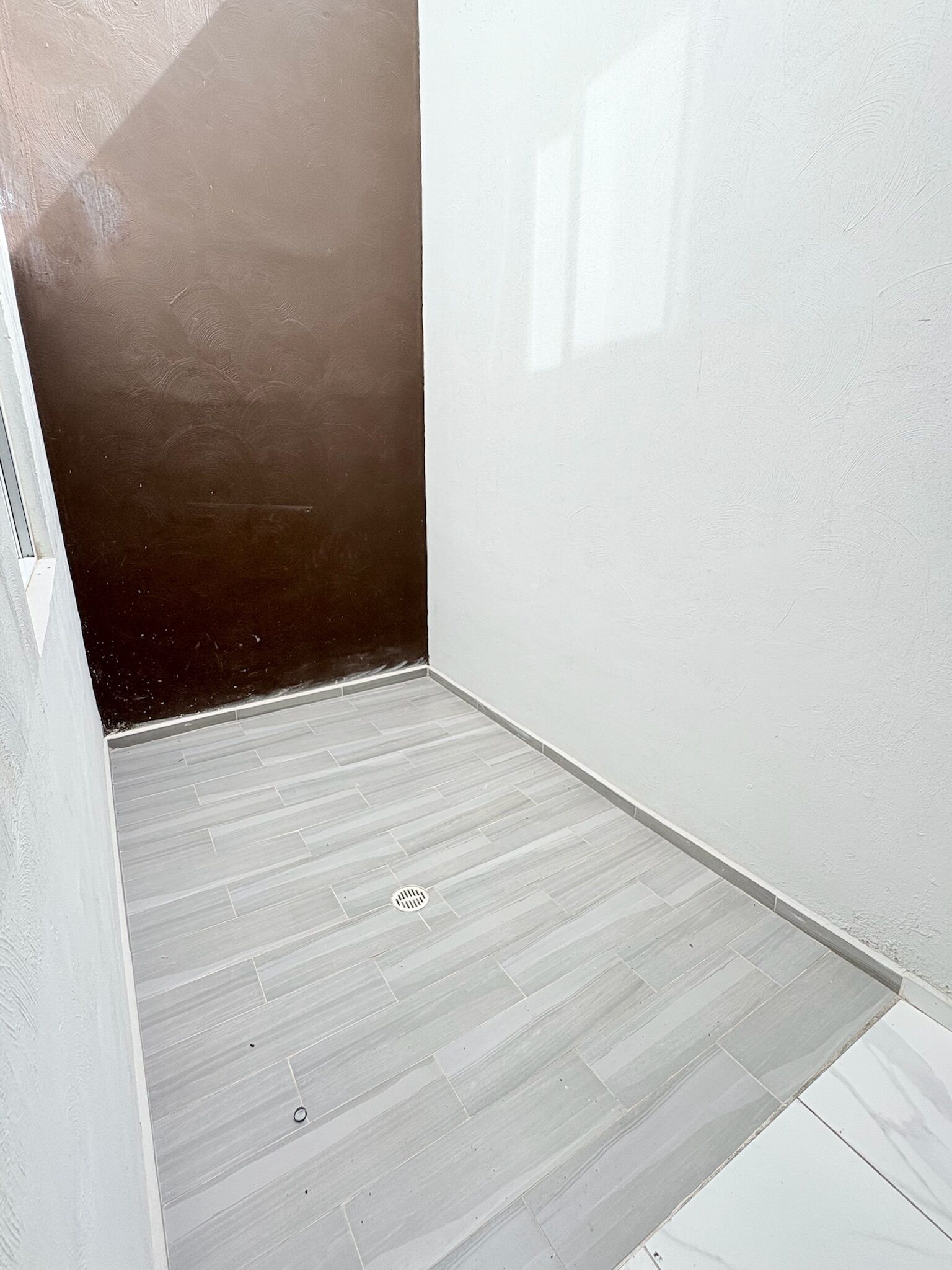 Une petite pièce fermée, avec un mur de couleur sombre et un plancher de couleur claire.
