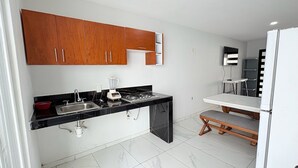 A modern kitchen with wooden cabinets, a black countertop, and a built-in stove. - Residencial Gran Cobae Triplex A (Tonalá)