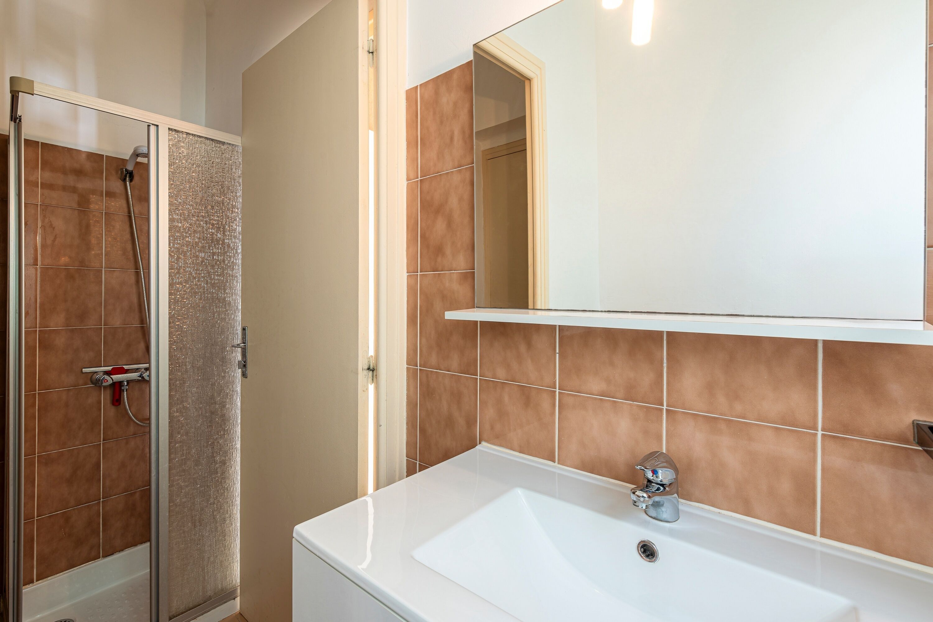 A bathroom with a shower, a sink, and a mirror.