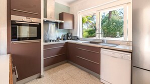 Una cocina moderna con horno integrado, lavavajillas Bosch y ventana con vistas a zonas verdes.