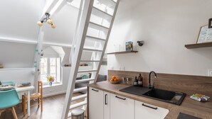 Una cocina moderna con encimera de madera, un lavamanos negro y una escalera blanca.