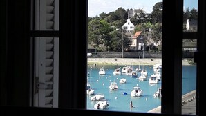 Vista de un puerto deportivo con barcos amarrados, un edificio con techo rojo y un aparcamiento en primer plano.