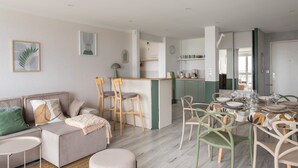 A modern living space with a sofa, dining table, and kitchen area. - L'Eperon - Proche Place Charles de Gaulle (Rennes)
