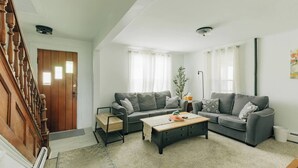 A living room with two grey sofas, a wooden coffee table, and a staircase.