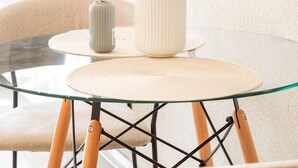 A round glass table with two vases on a textured placemat, set in a modern room with a neutral color palette and minimalist decor. - Central, sunny city apartment near Mercedes - top modern (Sindelfingen)