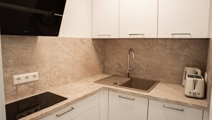 A modern kitchen with white cabinets, a built-in stove, a sink, and a toaster. - Central, sunny city apartment near Mercedes - top modern (Sindelfingen)