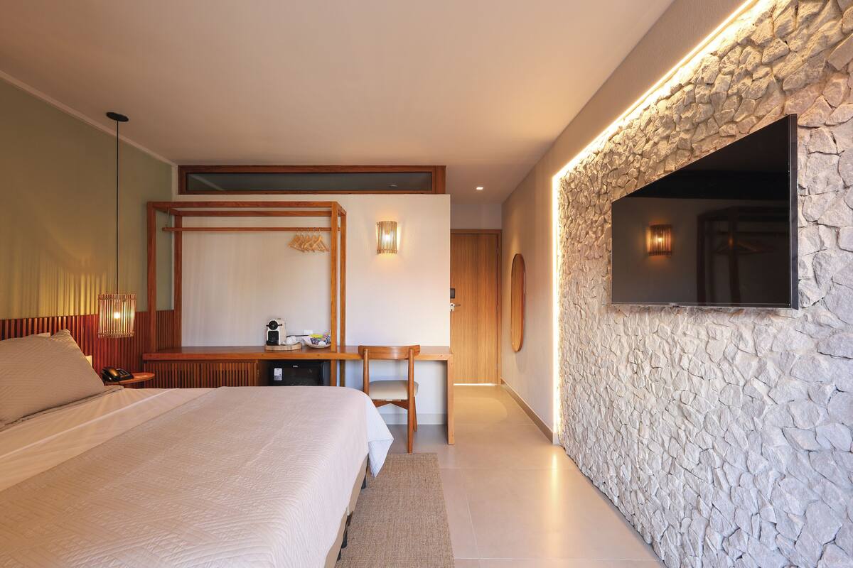 Ein modernes Hotelzimmer mit einem großen Bett, einem Schreibtisch und einer Wand mit Steinverkleidung.