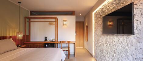 A modern hotel room with a large bed, a desk, and a stone accent wall.
