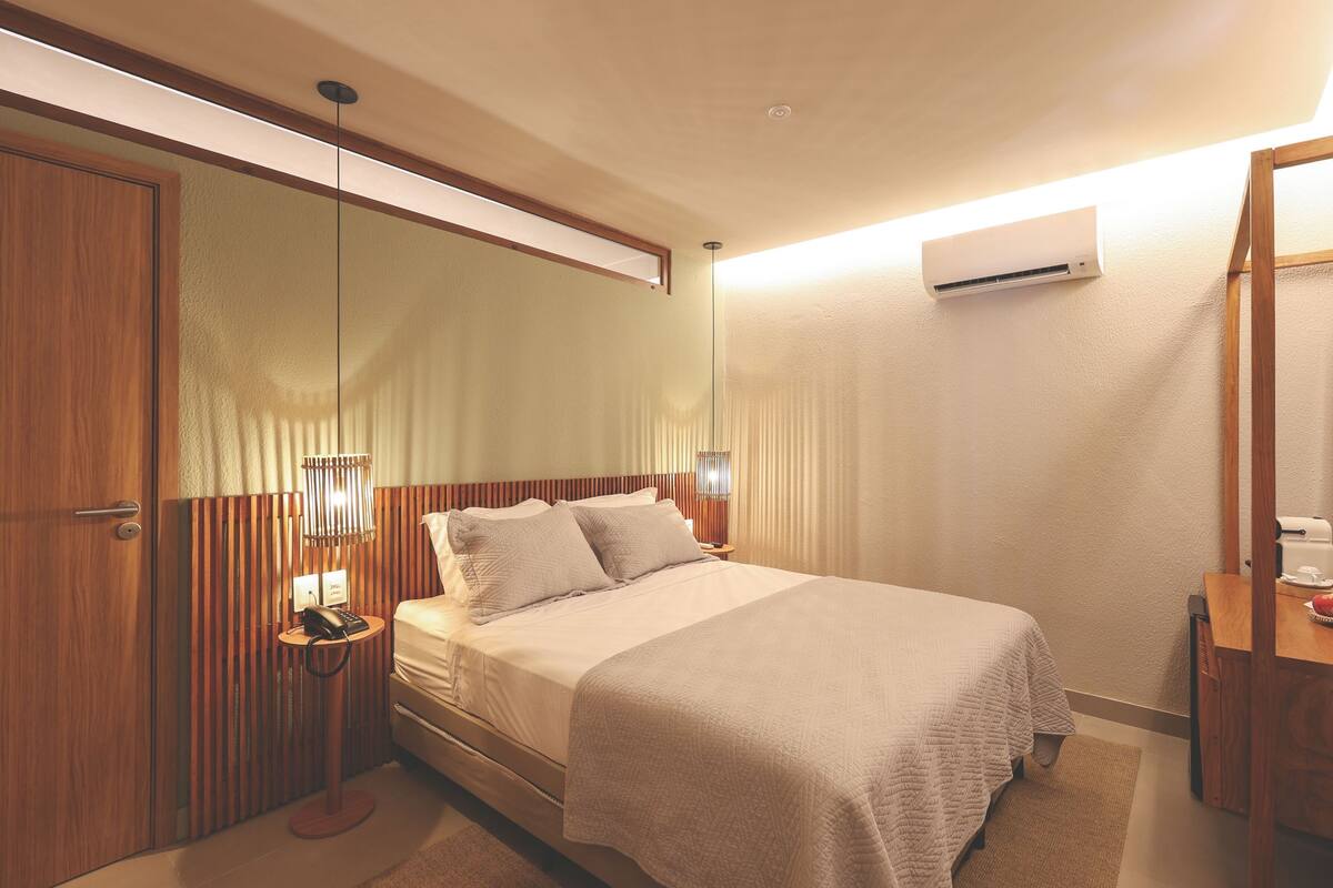 Ein Hotelzimmer mit Bett, Nachttisch, Lampe und Spiegel.