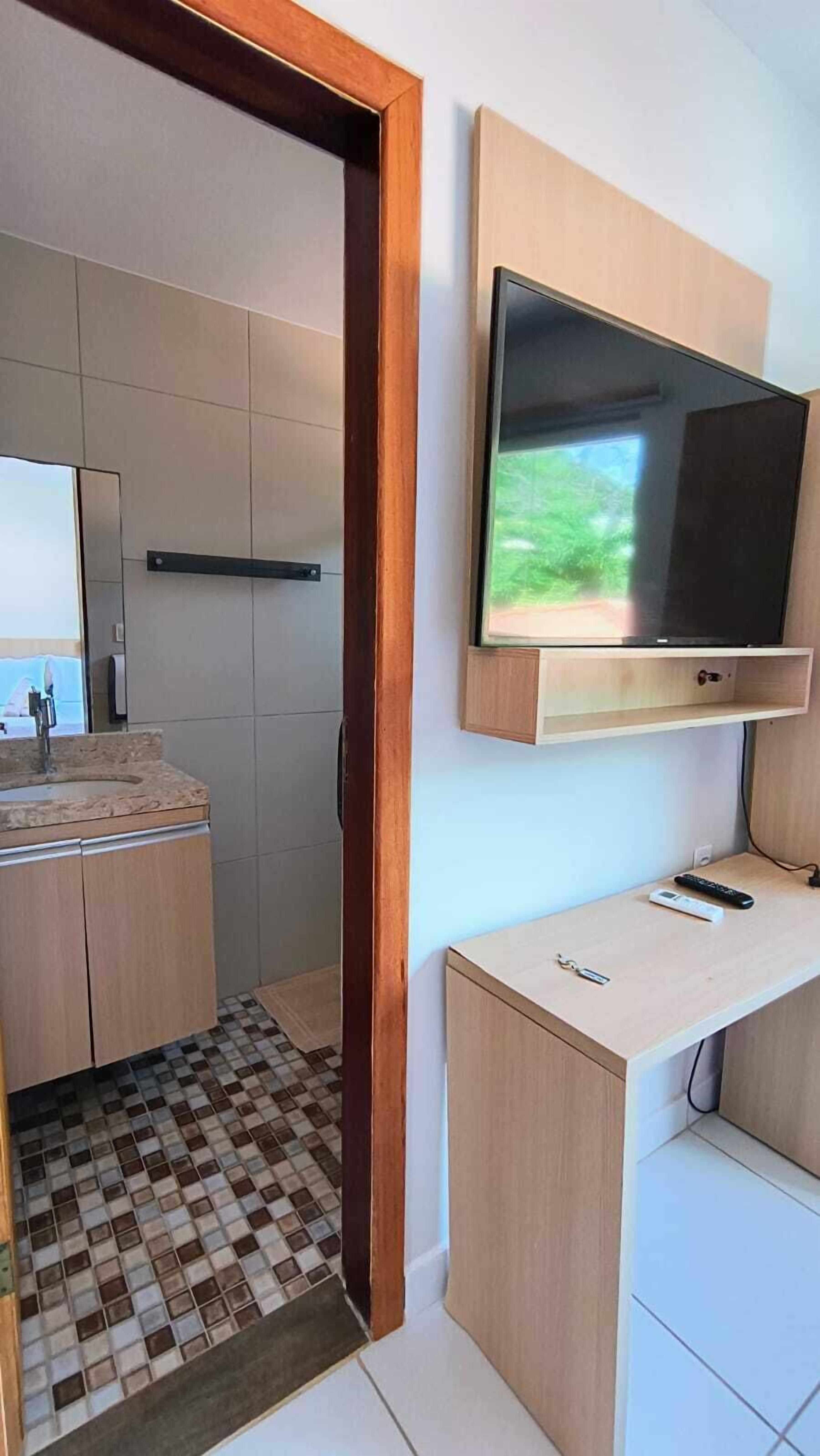 Un baño moderno con tocador de madera, un lavabo y un televisor montado.