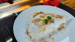 Une table à manger avec une assiette blanche contenant de la nourriture, une fourchette et une tasse.