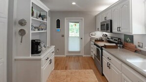 A kitchen with white cabinets, a microwave, an oven, and a coffee maker.