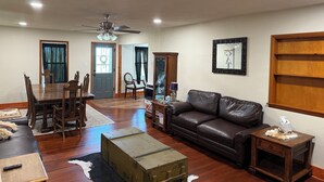 Un salón espacioso con comedor, un sofá de cuero, una mesita auxiliar y un baúl antiguo.