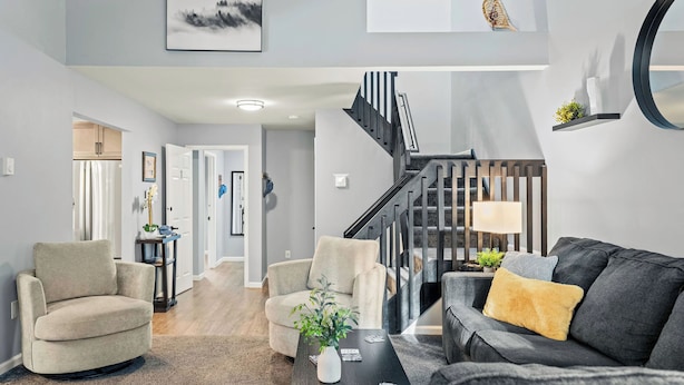 Una sala de estar moderna con una escalera, un comedor y una cocina a la vista en el fondo.