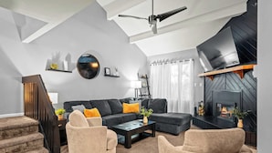 Una sala de estar moderna con un sofá modular, dos sillones, una mesa de centro y una chimenea.