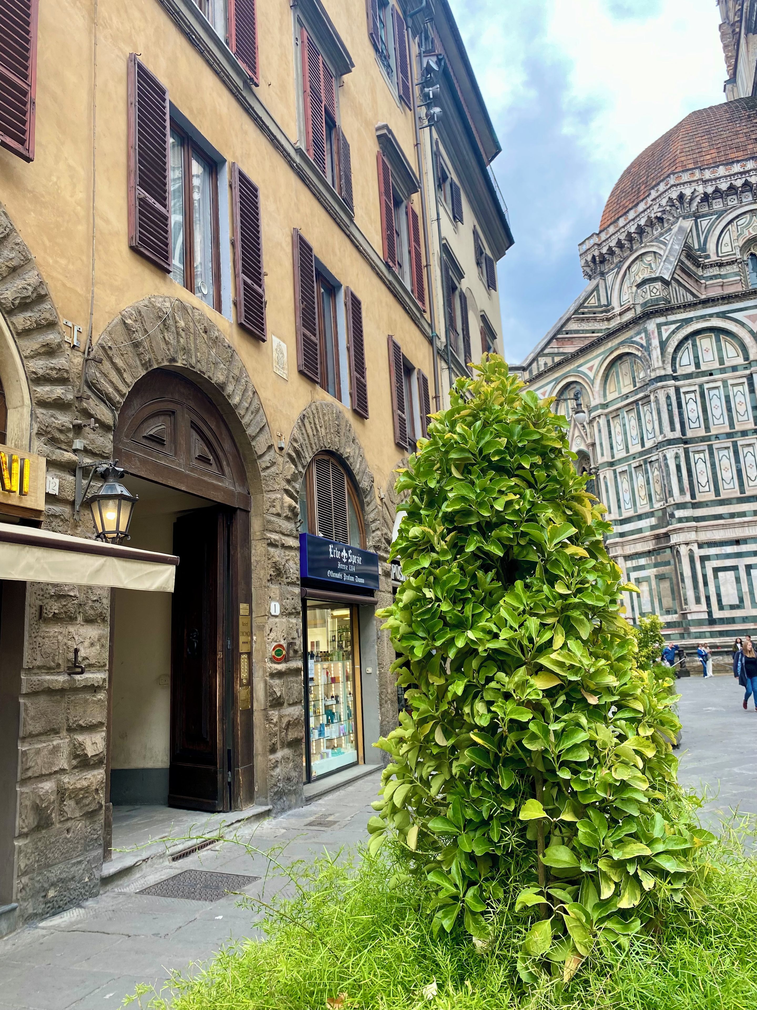 A building with a stone facade, arched doorways, and a shop with a sign in a foreign language.