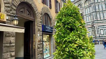 A building with a stone facade, arched doorways, and a shop with a sign in a foreign language.