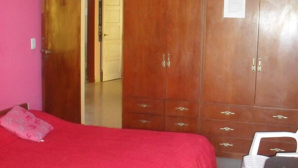 Quarto com duas camas, um guarda-roupa e uma cadeira.