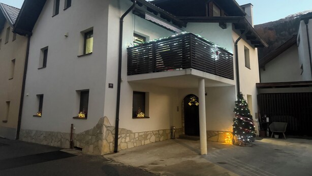 Une maison à deux étages avec un balcon, des fondations en pierre et un sapin de Noël.