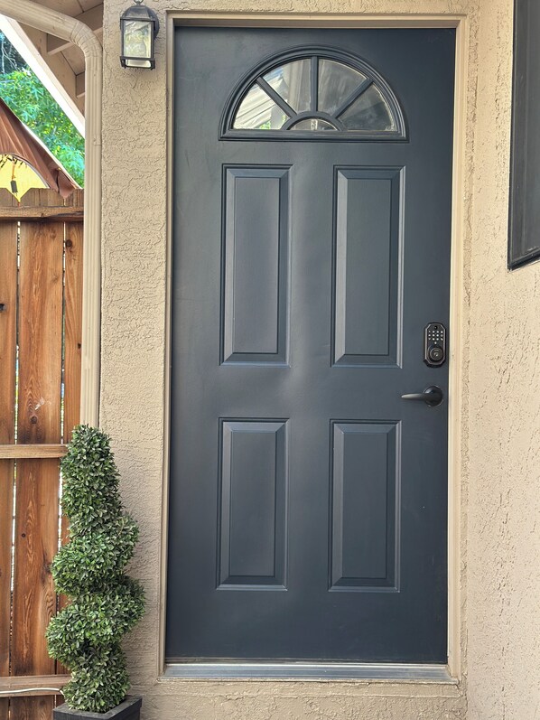 A dark gray front door with a glass peephole and a keypad lock.