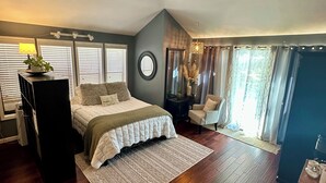 Een slaapkamer met een bed, een plafondventilator, een bureau en een raam met gordijnen.