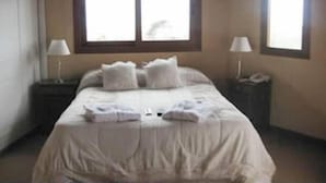 Une chambre à coucher avec un lit, deux tables de chevet et deux fenêtres.