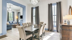 Un comedor con una gran mesa de madera, seis sillas tapizadas y un candelabro.