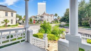 A balcony with a white railing overlooking a street with a historic building and a modern skyscraper in the background. - Walk to Strand District: Historic Galveston Home (Galveston)