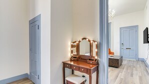 A room with a vanity, a mirror with lights, a chair, and a door. - 1 Mi to Pleasure Pier: Golden-Age Getaway! (Galveston)