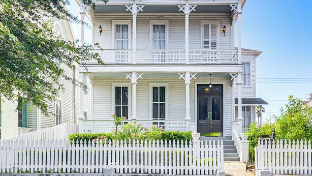 A two-story white house with a front porch, white picket fence, and a black front door. - 1 Mi to Pleasure Pier: Golden-Age Getaway! (Galveston)