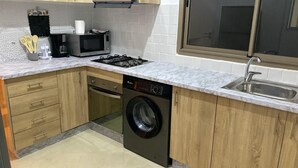 A compact kitchen with a washing machine, microwave, and sink. - Charming apartment for rent in Kenitra - Oriental & rustic style 🏡 (Kénitra)