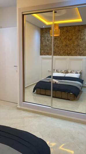 A bedroom with a large sliding glass door, a bed with a dark headboard, and a wall with a textured pattern. - Charming apartment for rent in Kenitra - Oriental & rustic style 🏡 (Kénitra)