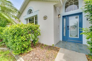 A house with a blue door, a small garden, and a sign on the wall.